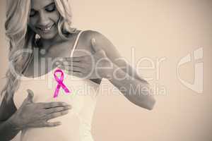 Woman with pink ribbon touching breast