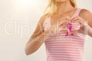 Mid section of woman making heart shape with hands over ribbon