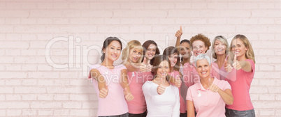 Composite image of portrait of female friends showing thums up sign for breast cancer awareness