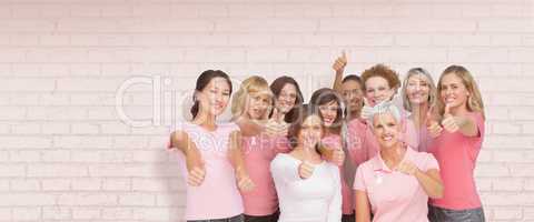 Composite image of portrait of female friends showing thums up sign for breast cancer awareness