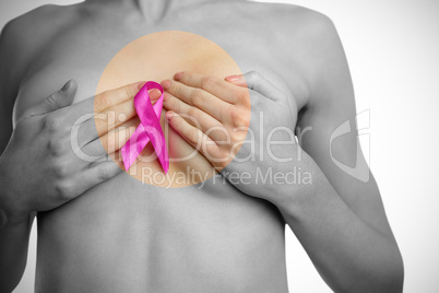 Midsection of naked woman with pink ribbon covering breast