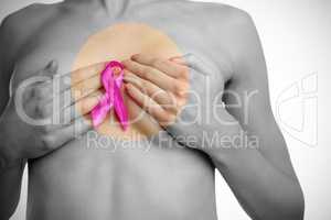 Midsection of naked woman with pink ribbon covering breast