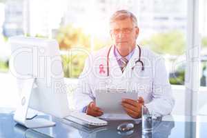 Composite image of portrait of confident male doctor sitting at computer desk