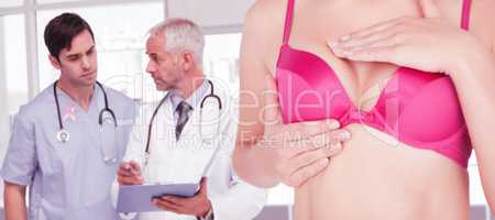 Composite image of mid section of woman in pink bra checking breast for cancer awareness