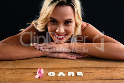 Portrait of woman by table with ribbon and care text