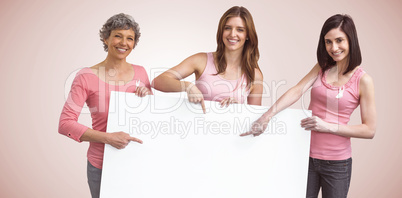 Composite image of women in pink outfits holding board for breast cancer awareness