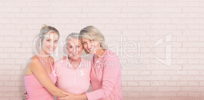 Composite image of portrait of smiling daughters with mother supporting breast cancer awareness