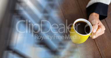 Overhead of hand with yellow coffee cup and blurry window transition