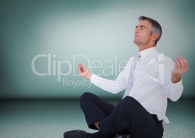 Business man meditating against green wall