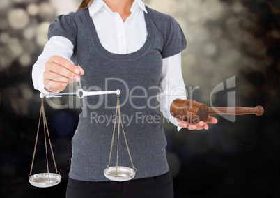 Female judge mid section with scales and gavel against dark bokeh