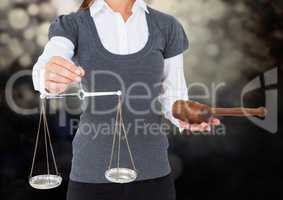 Female judge mid section with scales and gavel against dark bokeh