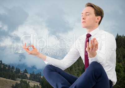 Business man meditating against mountains and trees