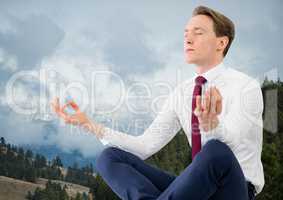 Business man meditating against mountains and trees