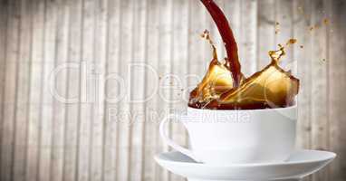 Coffee being poured into white cup against blurry wood panel