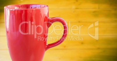 Red cup against blurry yellow wood panel