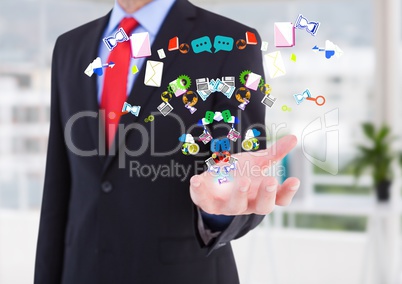 Businessman hand spread of with application icons coming up from it in the office ( blurred)