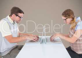 Nerd couple at laptops against brown background