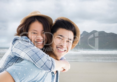 Couple piggy back against blurry beach