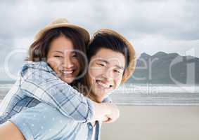 Couple piggy back against blurry beach