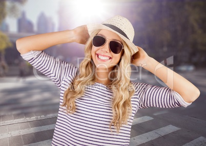 Woman in summer clothes with hands on head against blurry street with flare