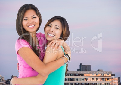 Best friends hugging against buildings and evening sky