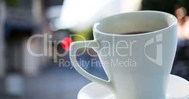 Coffee cup and saucer against blurry street