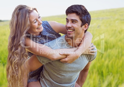 Couple piggy back against blurry meadow