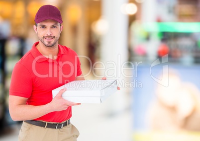 Delivery man with pizza box against blurry shopping centre