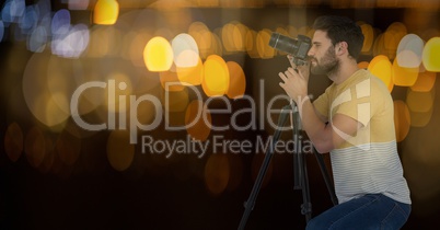 photographer taking a photo with the camera on the tripod. Blue and yellow bokeh background and boke