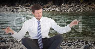 Business man meditating on riverbank