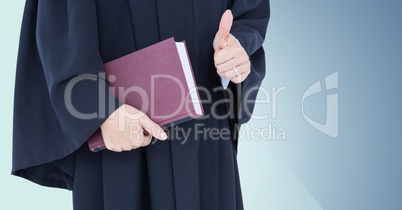 Female judge mid section with book and thumbs up against blue background