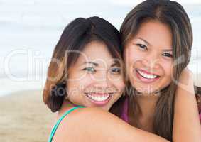 Best friends hugging against blurry beach