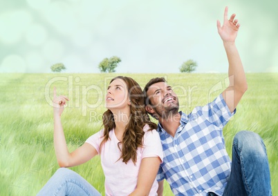 Couple sitting and pointing in meadow