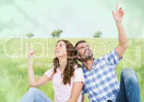 Couple sitting and pointing in meadow