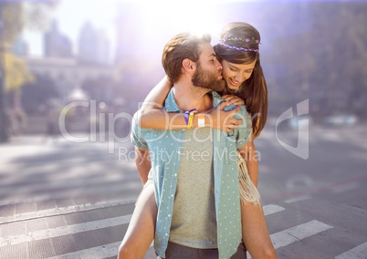 Couple piggy back against blurry street with flare