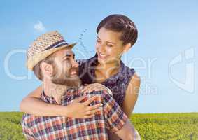 Couple piggy back in field on summer day