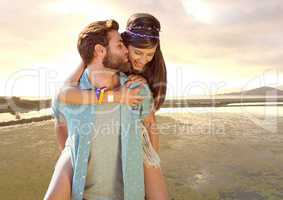 Millennial couple piggy backing against river at evening