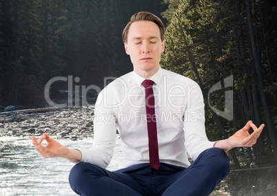 Business man meditating against river