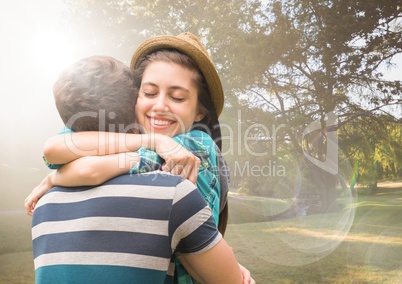 Couple hugging in blurry park with flares