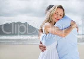 Couple hugging against blurry beach