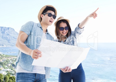 Millennial couple with map against blurry coastline