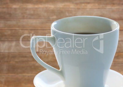 White coffee cup with saucer against blurry wood panel