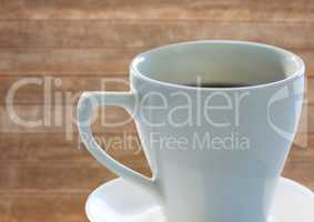 White coffee cup with saucer against blurry wood panel