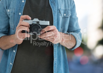 photographer hands with vintage camera ( foreground) in the city ( blurred lights)