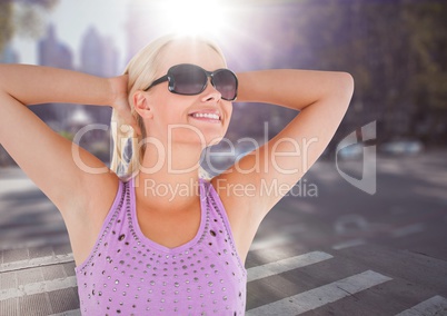 Woman in sunglasses stretching against blurry street with flare
