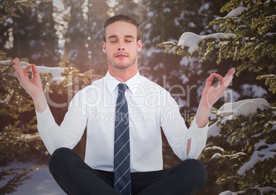 Business man meditating  against snowy trees