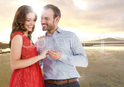 Couple engaged against river in evening with flare