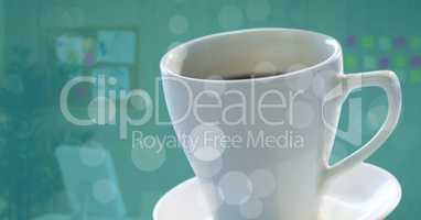 White coffee cup on saucer with bokeh against blurry office with teal overlay