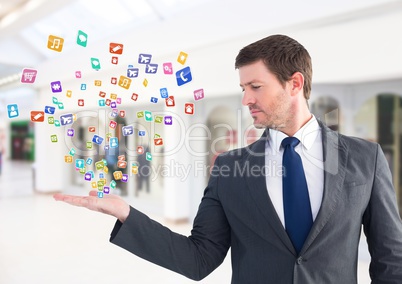 Business man  with hand spread of  with application icons coming up form it.  Blurred office backgro