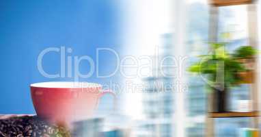 Red coffee cup on red and white table cloth with beans against blue background and blurry window tra